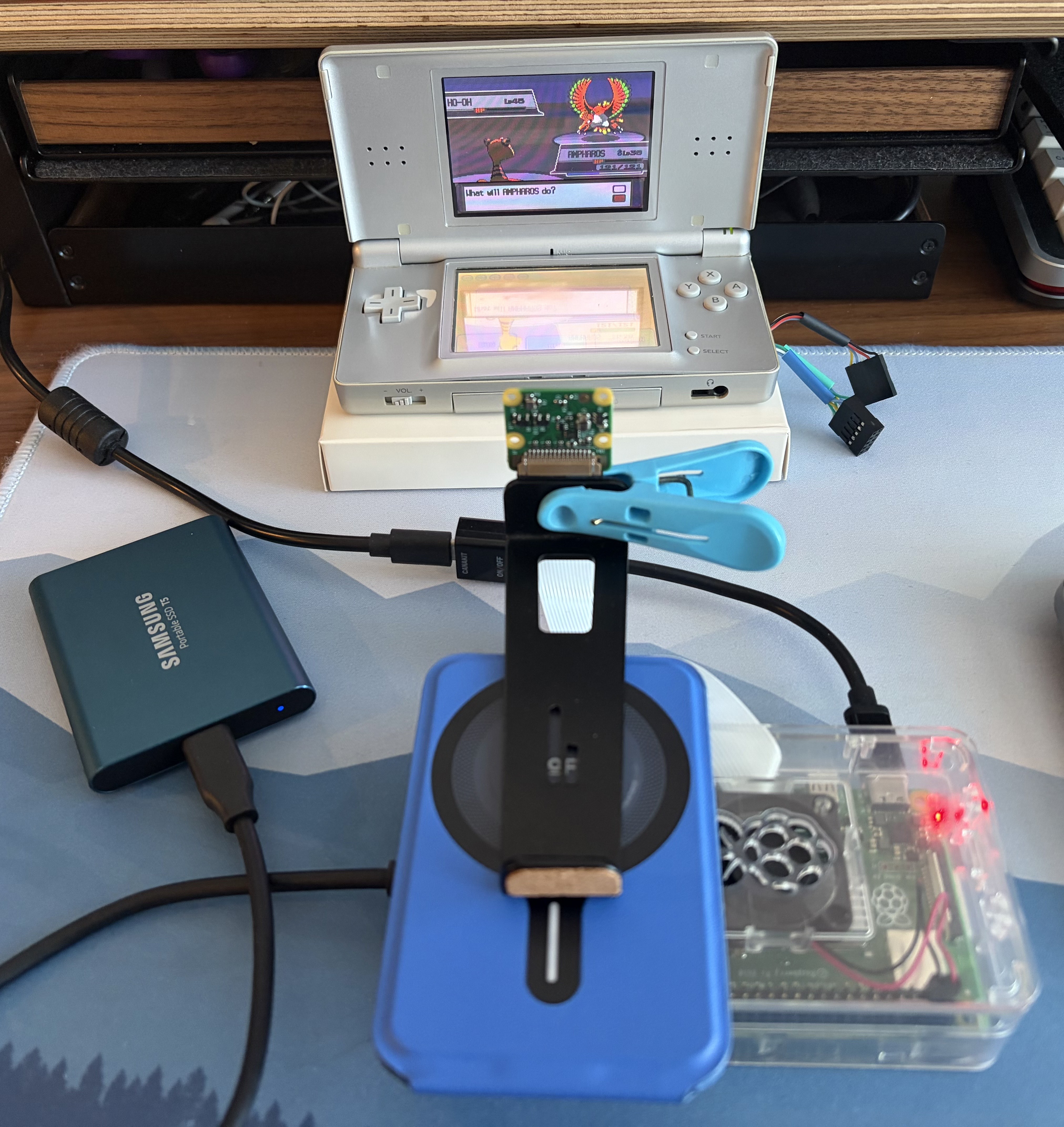 DS Lite facing a camera held by a clip and stand, with the Raspberry Pi beside it